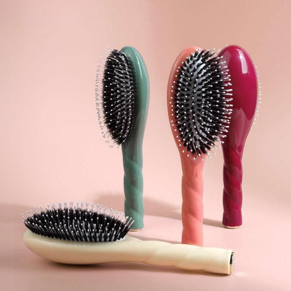 brosse cheveux multicolore présentée en quatre teintes sur fond rose